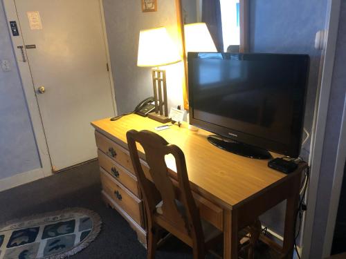 einen Schreibtisch mit einem TV und eine Kommode mit einer Lampe in der Unterkunft Wells River Motel in Wells River