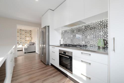 a kitchen with white cabinets and a stove top oven at Sapphire Spring Rise in Wanaka
