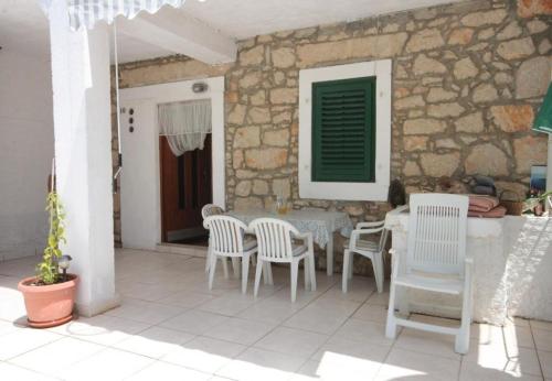 een patio met een tafel en stoelen en een stenen muur bij Apartments Tonci - 30 m from beach in Kali