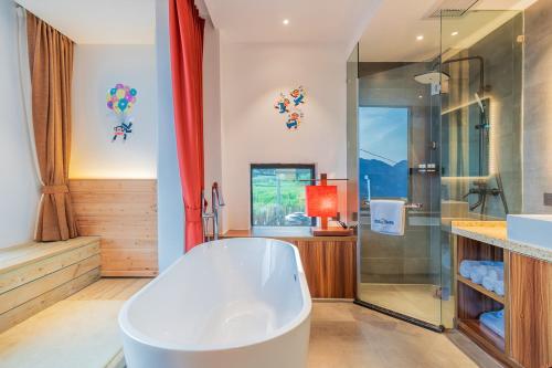 a bathroom with a tub and a glass shower at Enshi Grand Canyon Yutan Muyun Guesthouse in Enshi