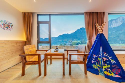 a room with a table and chairs and a large window at Enshi Grand Canyon Yutan Muyun Guesthouse in Enshi