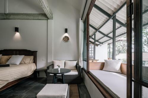 a bedroom with a bed and a table and a chair at Palin Family Cottage in Chiang Rai