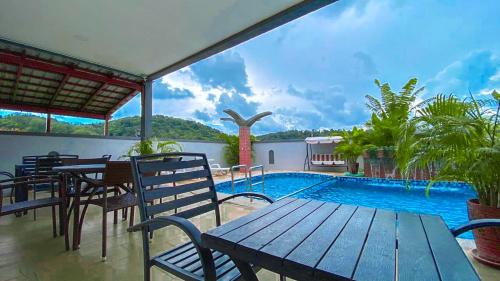 a patio with a table and chairs and a swimming pool at Norshah Village Resort in Pantai Cenang