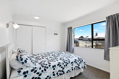 芒格努伊山的住宿－Mt Beach Retreat - Mt Maunganui Holiday Home，一间卧室设有一张床和一个大窗户