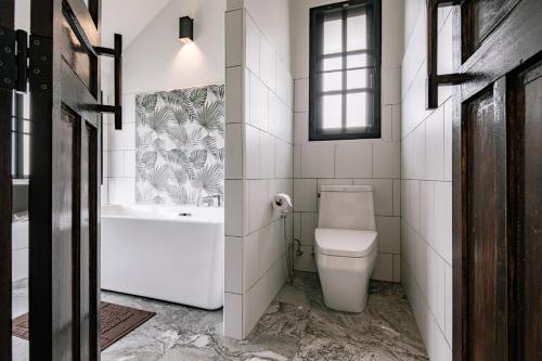 a bathroom with a toilet and a tub and a sink at Palin Family Cottage in Chiang Rai