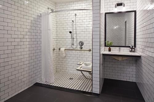 a white tiled bathroom with a shower and a sink at Pacific View Inn in San Diego