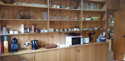 a kitchen with wooden shelves with a microwave on a counter at New Horizons Farm Stay in Smeaton