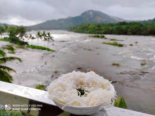 a white flower sitting on a table next to a river at The Anchorage Athirapilly Resort in Athirappally