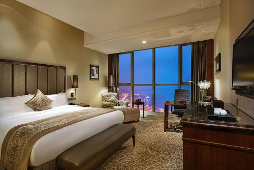 a hotel room with a bed and a desk and a large window at Crowne Plaza Zhenjiang, an IHG Hotel in Zhenjiang
