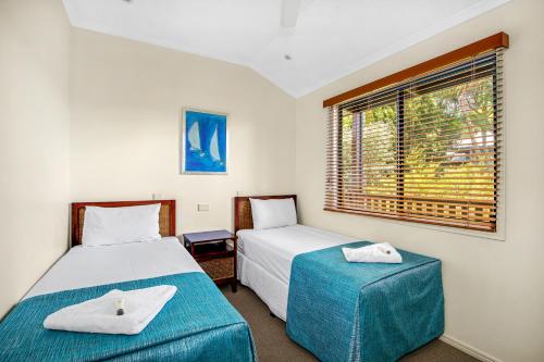 a bedroom with two beds and a window at Tin Can Bay Marina Villas in Tin Can Bay
