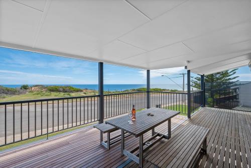 a deck with a table and a view of the ocean at Beach House at Moana - C21 SouthCoast Holidays in Moana