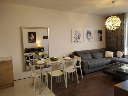 a living room with a couch and a table and chairs at Sunny Penthouse with roof gardens overlooking the Warsaw Palace of Culture in Pruszków