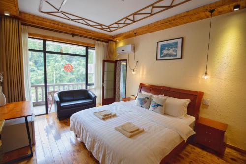een slaapkamer met een bed met een stoel en een raam bij Moganshan Bamboo View Guesthouse in Deqing