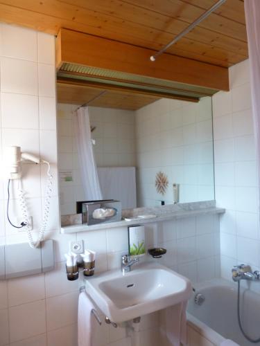 a bathroom with a sink and a tub and a mirror at Hotel Ermitage Verbier in Verbier