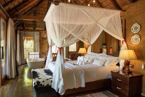 een slaapkamer met een hemelbed en een bad bij Jabulani Safari in privé-wildreservaat Kapama