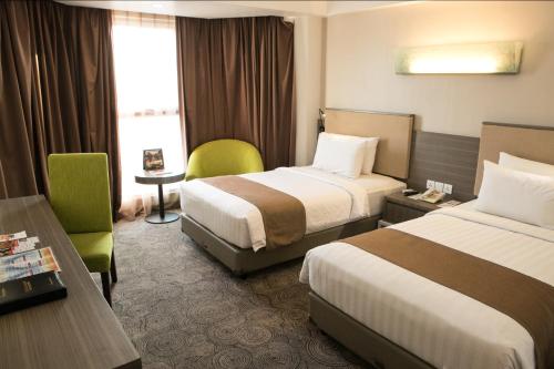 a hotel room with two beds and a desk at Swiss-Belhotel Borneo Samarinda in Samarinda