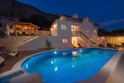 una piscina davanti a una casa di notte di Luxury VILLA MAJA with whirlpool, heated pool, gym, sauna, panoramic sea views a Jesenice
