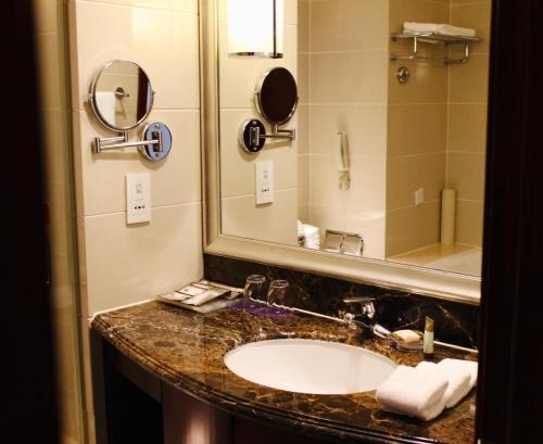 ein Bad mit einem Waschbecken und einem Spiegel in der Unterkunft Tianjin Saixiang Hotel in Tianjin