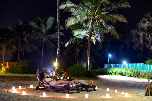 two people laying in chairs on the beach at night at The Zuri White Sands, Goa Resort & Casino in Varca
