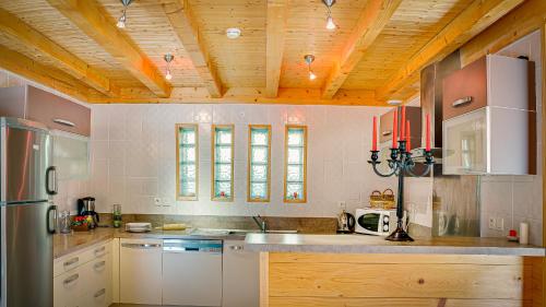 une grande cuisine avec un plafond en bois et des comptoirs en bois dans l'établissement Tarine - Chalet - BO Immobilier, à Châtel