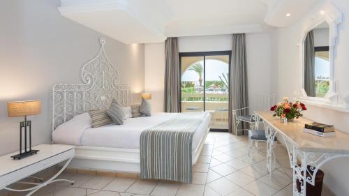 Djerba Aqua Resort في ميدون: غرفه فندقيه بسرير ومكتب ونافذه