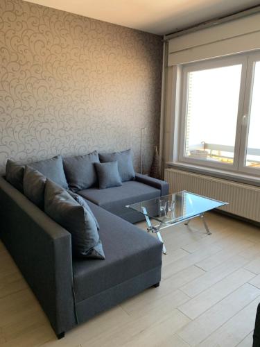a living room with a couch and a glass table at Appartement met zeezicht in Blankenberge