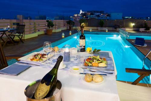 a table with food and wine next to a swimming pool at Hotel Royal Plaza in Ibiza Town