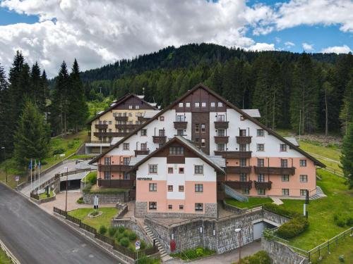 a group of buildings on a hill with trees at Nevesole Folgarida Resort Aparthotel in Dimaro