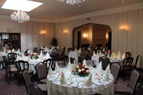 a banquet room with white tables and chairs and chandeliers at Oakwood Hall Hotel in Bingley