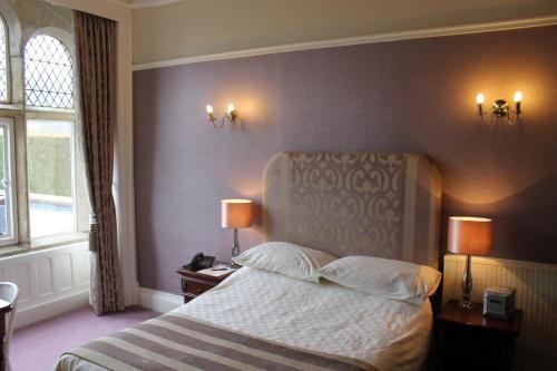 a bedroom with a bed with two lamps and two tables at Oakwood Hall Hotel in Bingley