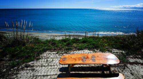 a wooden bench sitting on the side of a beach at The Waters in Motueka