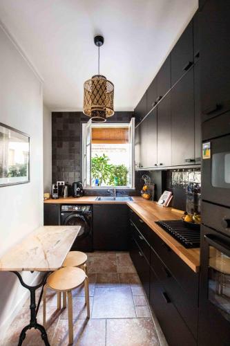 une cuisine avec des armoires noires et une table en bois dans l'établissement Veeve - Pastel Pinks in Paris, à Paris