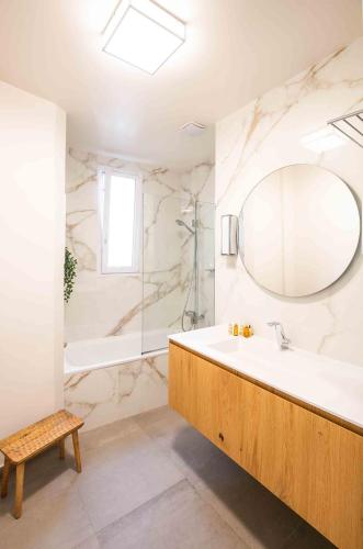 une salle de bain avec une baignoire, un lavabo et un miroir dans l'établissement Veeve - Pastel Pinks in Paris, à Paris