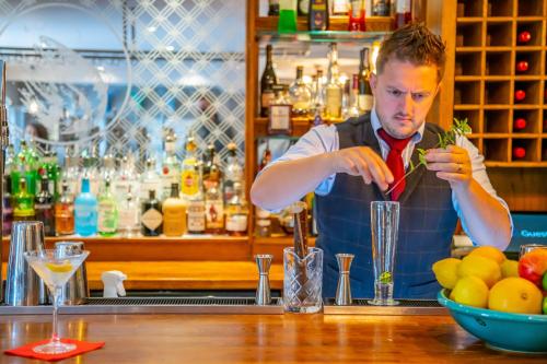 a man making a drink at a bar at Banchory Lodge Hotel in Banchory