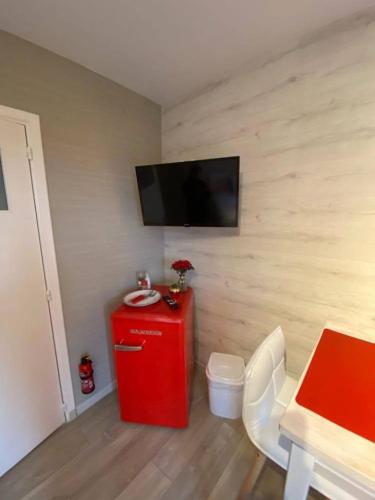 a room with a red refrigerator and a tv on a wall at La Milardière Chambres d'Hôtes in Theux