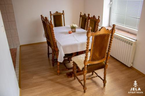 a dining room table with a white tablecloth and chairs at Apartman Jela in Kupres