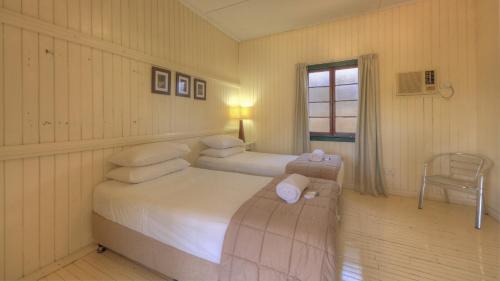 a bedroom with two beds and a chair and a window at Wellshot Hotel in Ilfracombe