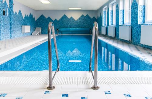 uma piscina interior com paredes de azulejos azuis em Horský Hotel Podjavorník em Papradno