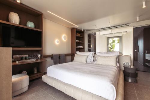 a bedroom with a large white bed and a flat screen tv at Santana Beach in Agia Anna Naxos