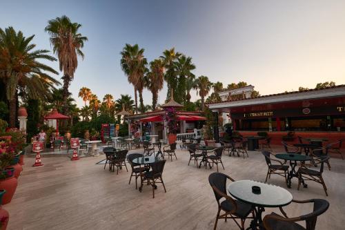 a patio with tables and chairs and palm trees at Club Hotel Sera in Antalya