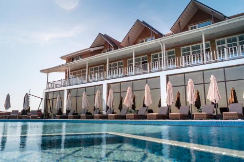 ein Hotel mit einem Pool mit Stühlen und Sonnenschirmen in der Unterkunft Спа-Готель Потоки Хауз in Kam”yani Potoky