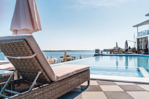 a wicker chair with an umbrella next to a swimming pool at Спа-Готель Потоки Хауз in Kam”yani Potoky