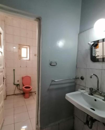 a bathroom with a red toilet and a sink at Winji Guest house in Aswan