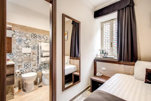 Un baño con un inodoro, un lavabo y un espejo. en Rome Garden Hotel, en Roma