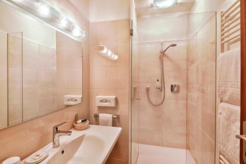 a bathroom with a glass shower and a sink at Hotel Juliane in Merano