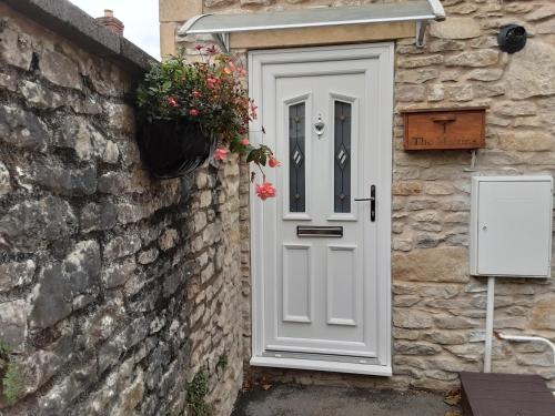a white door on a stone building with a potted plant at The Maltings - Apartments 1 in Shepton Mallet