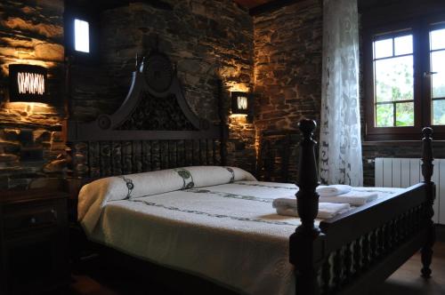 1 dormitorio con 1 cama en una pared de piedra en APARTAMENTOS RURALES CASTRO DE VILAOSENDE en Ribadeo