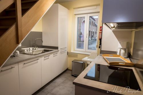 a kitchen with white cabinets and a sink and a window at Les gîtes du Broukay - Alouette in Bassenge