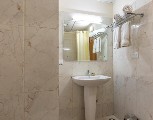 a bathroom with a sink and a shower with a mirror at KSTDC KumaraKrupa Hotel in Bangalore