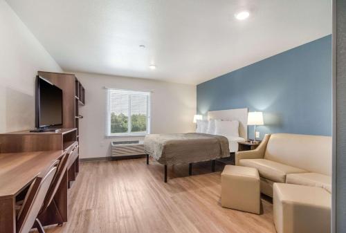 a small hotel room with a bed and a couch at WoodSpring Suites Fort Mill in Fort Mill